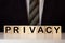 Close Up Of Person's Hand Protecting Blocks With Privacy Text On Wooden Desk