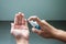 A close up of a person`s hand is spraying alcohol with disinfecting hands to protect against bacteria and viruses, preventing