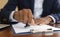 Close-up of a person`s hand stamping on an approved application form and approved contract form on paperwork at desk or a