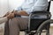 Close-up of person supporting paralysed senior woman on the wheelchair