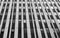 Close up perspective detail of tall high rise brutalist style office building with white vertical concrete lines and dark windows