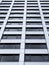 Close up perspective detail of tall high rose modern apartment building with white cladding and dark windows