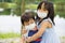 Close-up photo of adorable siblings hugging each other playfully wearing face mask