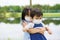 Close-up photo of adorable siblings hugging each other playfully wearing face mask