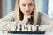 Close-up photo of a blonde woman playing chess, thoughtfully making a move