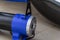 Close up photo of the blue automobile compressor, standing next to the car wheel. Electric pump inflates the flat tire. Selective