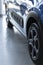 Close-up photo of blue shiny car with black wheels standing in car showroom interior