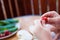 Close-up photo of boyÂ´s hands as he torns a stem from strawberry, before eating it. Photo is taken on terace, next to a table.