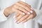 Close-up photo of elegant light pink manicure over white shirt background, tender women`s hands with perfect nails