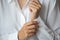 Close-up photo of elegant light pink manicure over white shirt background, tender women`s hands with perfect nails