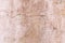 A close up photo of an exterior textured wall dirty pink color, surface with stucco daub, great for background