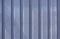 Close up photo of a facade from an industrial building with graphic stripes of minimalistic vertical blue weathered metal profiles