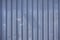 Close up photo of a facade from an industrial building with stripes of minimalistic weathered vertical metal profiles. Background