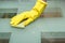 Close-up photo of female hand washing glass table in with cleaning spray and sponge wearing gloves in apartment