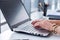 Close-up photo of female hands with accessories working on portable computer in a modern office, using keyboard.