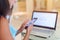 Close-up photo of female hands holding a smartphone with computer laptop in background. Young woman working on cellphone