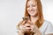 Close up photo. focus on the smartphone with a smiling ginger girl