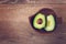 Close-up photo of fresh sliced avocados in brown bowl on brown wooden background. Top view. Copy space.