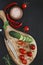 Close-up photo of fresh vegetables on wooden cutting board with knife on black concreted table background. Top view