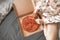 Close-up photo of a girl in a pajama sits on the bed and takes a piece of pizza from the box. Girl`s legs and a box of pizza,