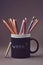 Close-up photo of a group multicolored pencils in black mug.