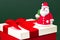 Close-up photo of gypsum colorful santa claus on the gift box over green background.