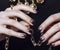 Close up photo hands with gold manicure holding chain on black