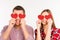 Close up photo of happy couple in love hiding eyes behind paper hearts