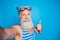 Close up photo of joyful pensioner with white hair making selfie showing thumb up sign wearing striped  over