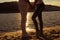 Close up photo of legs of man and woman watching sundown at the seaside