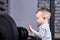 Close-up photo of little boy with barbell against brick wall in the cross fit gym.