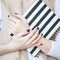 Close-up photo of manicured woman`s hands hold an elegant notebook with black and white strips
