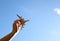 Close up photo ofwo man\'s hand holding toy airplane against blue sky with clouds