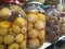 Close-up photo of pickled apple, pine cone, mandarin and medlar in the glass jars at asian food bazaar.