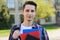 Close-up photo portrait of handsome sincere friendly guy holding several notepads in hands standing in front of campus building