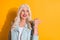 Close up photo portrait of pretty cool stylish grandmother pointing to the side copyspace isolated bright color yellow