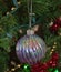 A close up photo of a rainbow glass Christmas bulb ornament on a Christmas tree