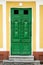 Close up photo of rare ancient antique green door on the yellow or orange wall