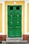 Close up photo of rare ancient antique green door on the yellow or orange wall