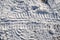 Close-up photo of a road in the winter season. On the dirty snow, a protector is visible from the tires of the truck