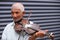 Close up photo of a senior adult musician gray-hair man playing the violin outdoors and turned his head to the side is