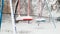 Close up photo of snow covered playground after blizzard. Blue and red swing under snow