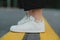 Close up photo of stylish white sneakers on asphalt road, forest background. Stylish closeup photo of fashionable sneakers on the
