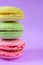 Close up photo of three french cookies with different interlayers one on top of each other on stack on bright purple background