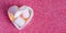 close up photo of three marshmallow in a tiny heart-shaped bowl on a pink glitter background