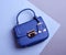 Close-up photo of a top-handle royal blue leather women\\\'s bag with metal hardware including a clasp, tag