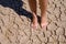 Close up photo of a womanâ€™s feet standing barefoot on a cracked earth, dried out land