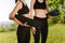 Close up photo of women bodies in black sporty tops and leggings standing and holding yoga mats in hands with beautiful