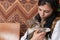 Close up photo of young woman in national black handkerchief holds grey cat in her hands