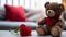 A close-up photograph where a lovable brown teddy bear takes center stage against a romantically blurred living room setting.